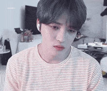 a young man wearing a striped t-shirt is looking at the camera .