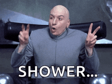 a bald man in a suit is giving a peace sign and has the word shower on his chest