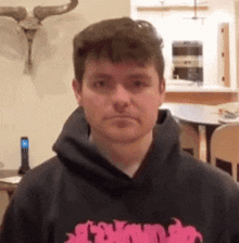 a man wearing a black hoodie is standing in a living room .