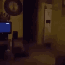 a person is walking through a dark room with a tv in the background .
