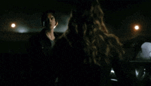 a man in a black jacket is standing next to a car at night