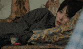a woman laying on a bed with a floral pillow