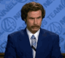 a man in a suit and tie is standing in front of a news team background