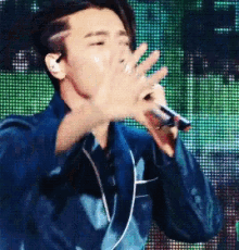 a man singing into a microphone in front of a large screen