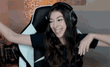 a woman wearing headphones is smiling while sitting in a gaming chair