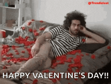 a man is laying on a bed covered in rose petals and wishing a happy valentine 's day .