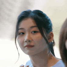 a close up of a woman 's face with a ponytail looking at the camera
