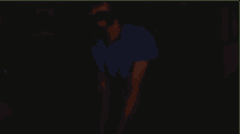 a man in a blue shirt is standing in a dark room with the word skye visible in the corner