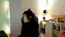 a woman sitting in a chair with a star on her head covering her face