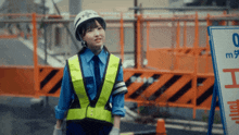 a woman wearing a helmet and safety vest stands in front of a sign that says 0m