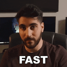 a man with a beard is sitting in a chair with the word fast above his head