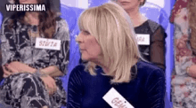 a woman in a blue dress is sitting in a row of people .