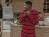 a man in a red and black striped shirt stands in a kitchen