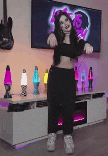 a woman in a black crop top is dancing in front of a tv .