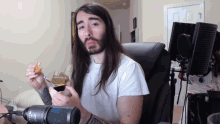 a man with long hair and a beard is eating food in front of a microphone that says ncr
