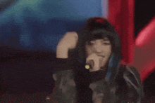 a woman with blue hair singing into a microphone in a dark room