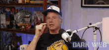 a man is sitting in front of a microphone wearing a hat that says s on it .