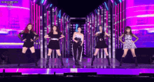 a group of women are standing on a stage dancing .