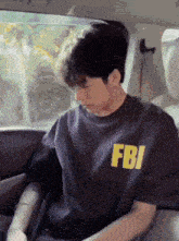 a man wearing a fbi shirt is sitting in a car