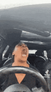 a woman is driving a car with her mouth open and yawning .