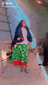 a woman wearing a blue veil and a green skirt is dancing in a room .