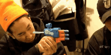 a man wearing an orange hat holds a toy gun