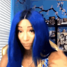 a woman with blue hair is standing in a room .