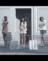 three women are dancing in front of a door with shopping bags in front of them
