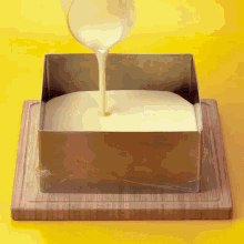 a cake is being poured into a metal pan on a cutting board