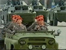 a group of soldiers are riding in a jeep with a military vehicle in the background