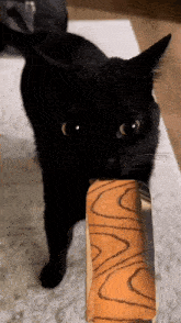 a black cat is holding a piece of bread in its mouth ..