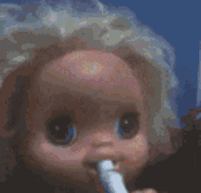 a close up of a baby doll with a toothbrush in its mouth .