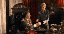 a man and a woman are sitting at a desk with a red cross on the desk