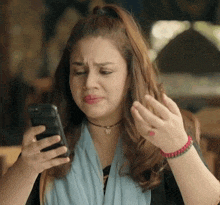 a woman with a butterfly necklace looks at her cell phone
