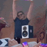 a man with his arms in the air is standing in front of a speaker that says ' a ' on it