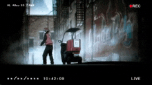 a man in a red jacket is standing next to a red box that says ' hl alley 33 ' on it