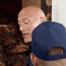 a bald man in a blue hat is talking to another man in a blue hat .