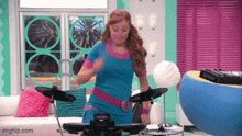 a girl in a blue shirt is playing a drum set in a living room ..