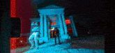 a man is standing in front of a building with columns and a red light .