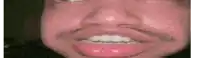 a close up of a man 's face with a mustache and white teeth making a funny face .