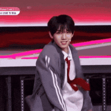 a young man is standing on a stage wearing a tie and a jacket .
