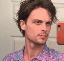 a man is taking a selfie in front of a mirror with his phone .