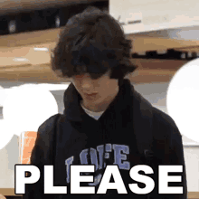 a young man wearing a black hoodie with the word please on it