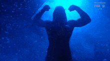 a silhouette of a man flexing his muscles in the water