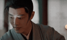 a man in a kimono is sitting at a table and looking at something .