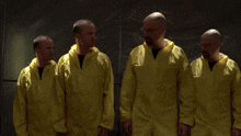 a group of men wearing yellow coveralls are standing in a row