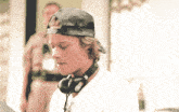 a man wearing headphones and a baseball cap has a white shirt on