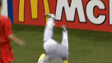 a soccer player is upside down in front of a mcdonald 's ad