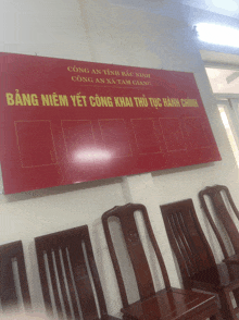 a row of wooden chairs in front of a red sign that says bang niem yet cong khai thu tuc hanh chinh