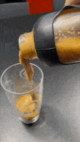a bottle is being poured into a glass with a few drops of liquid